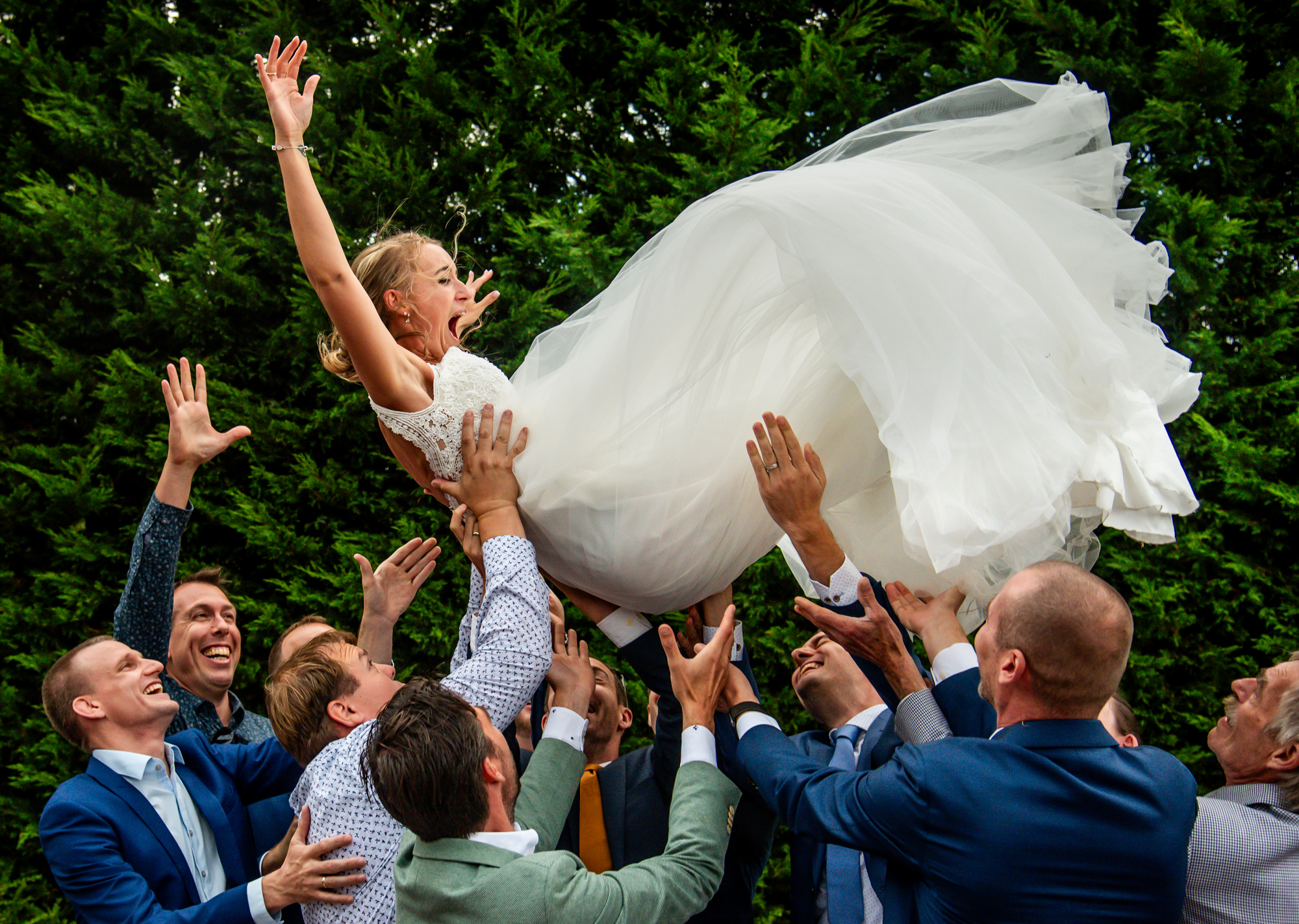 bruid wordt in de lucht gegooid tijdens de groepsfoto's